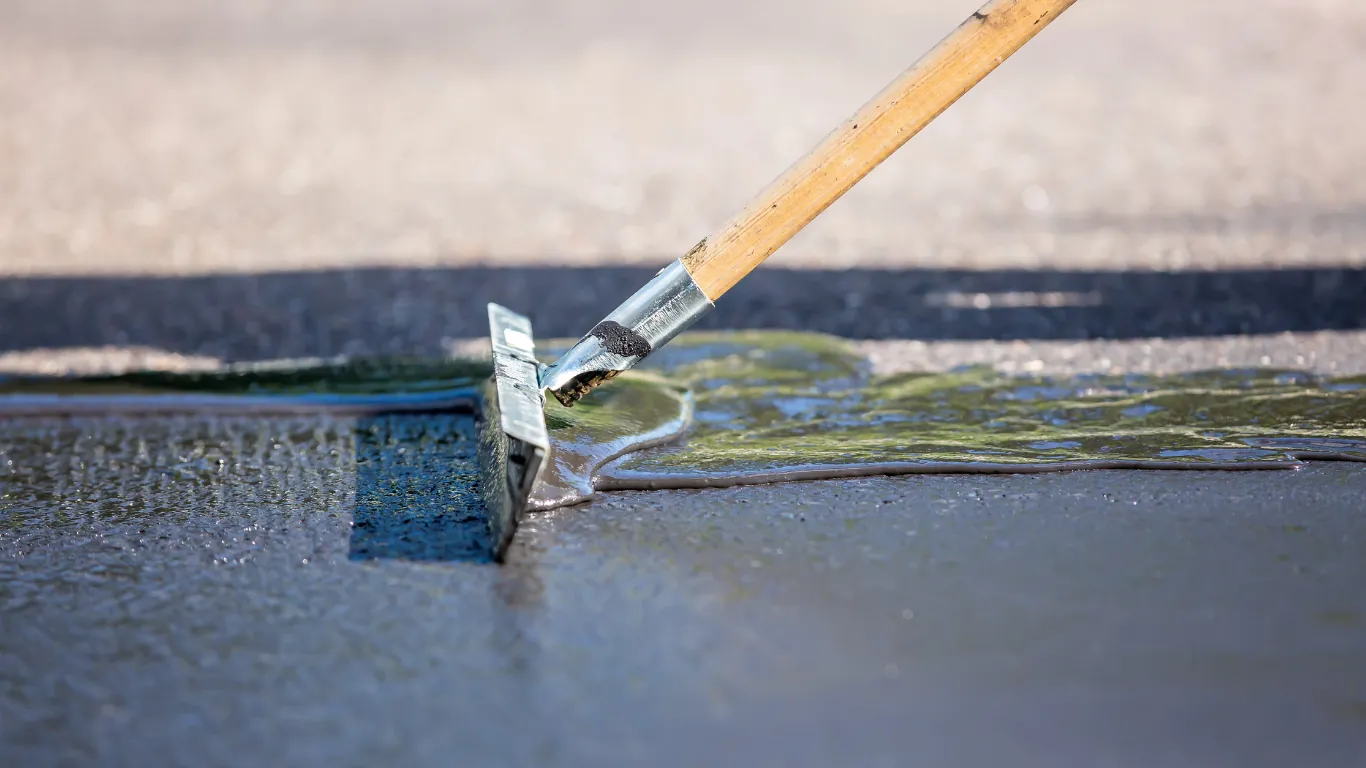 Hot rubberised crack sealant being pulled flush along a crack in asphalt